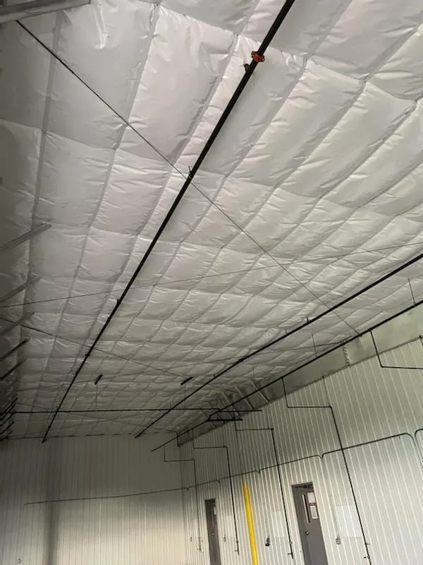 Metal building ceiling with white insulation installed between the purlins