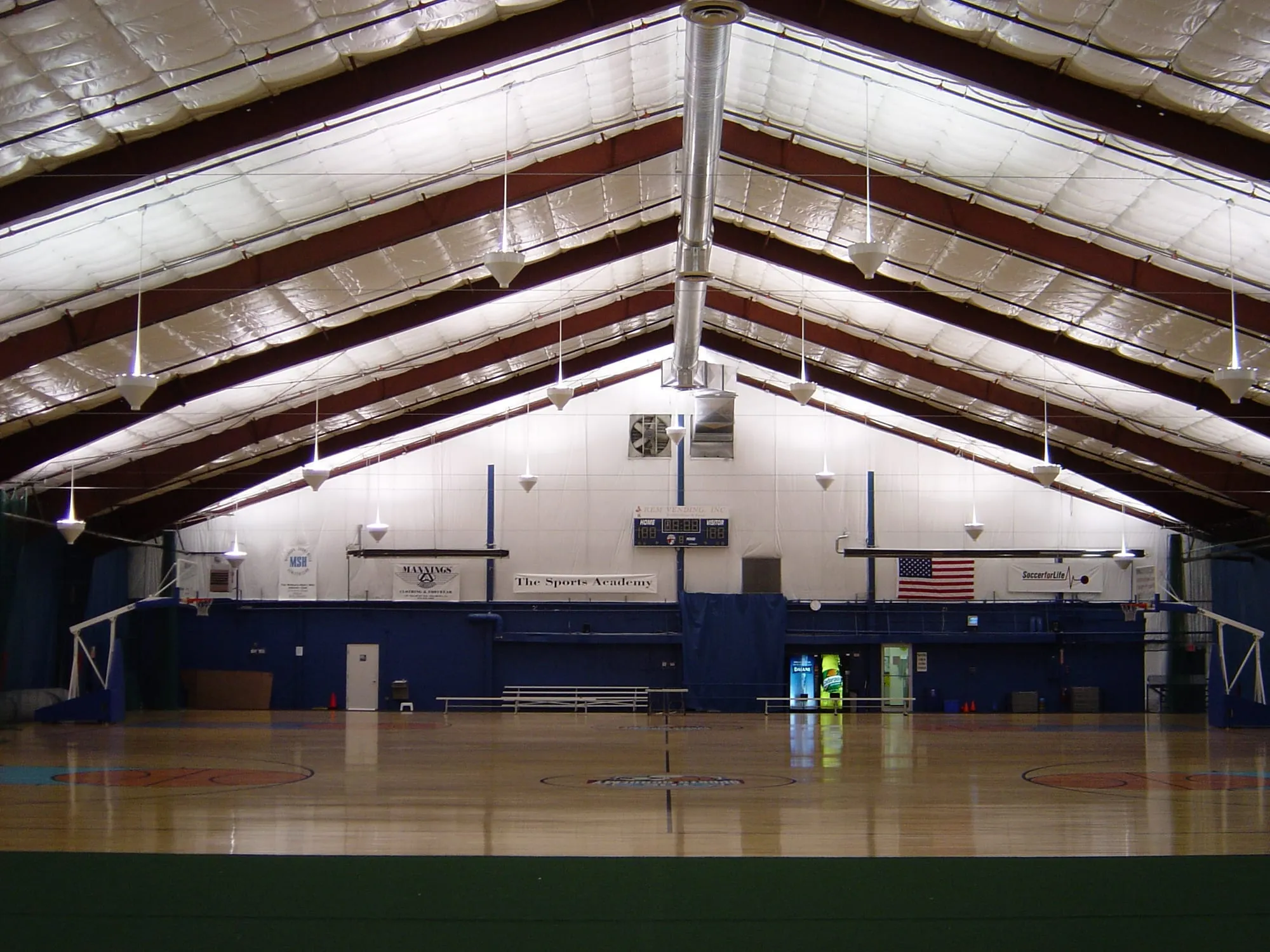 Insulation fitted between the roof rafters of an indoor sports academy gym